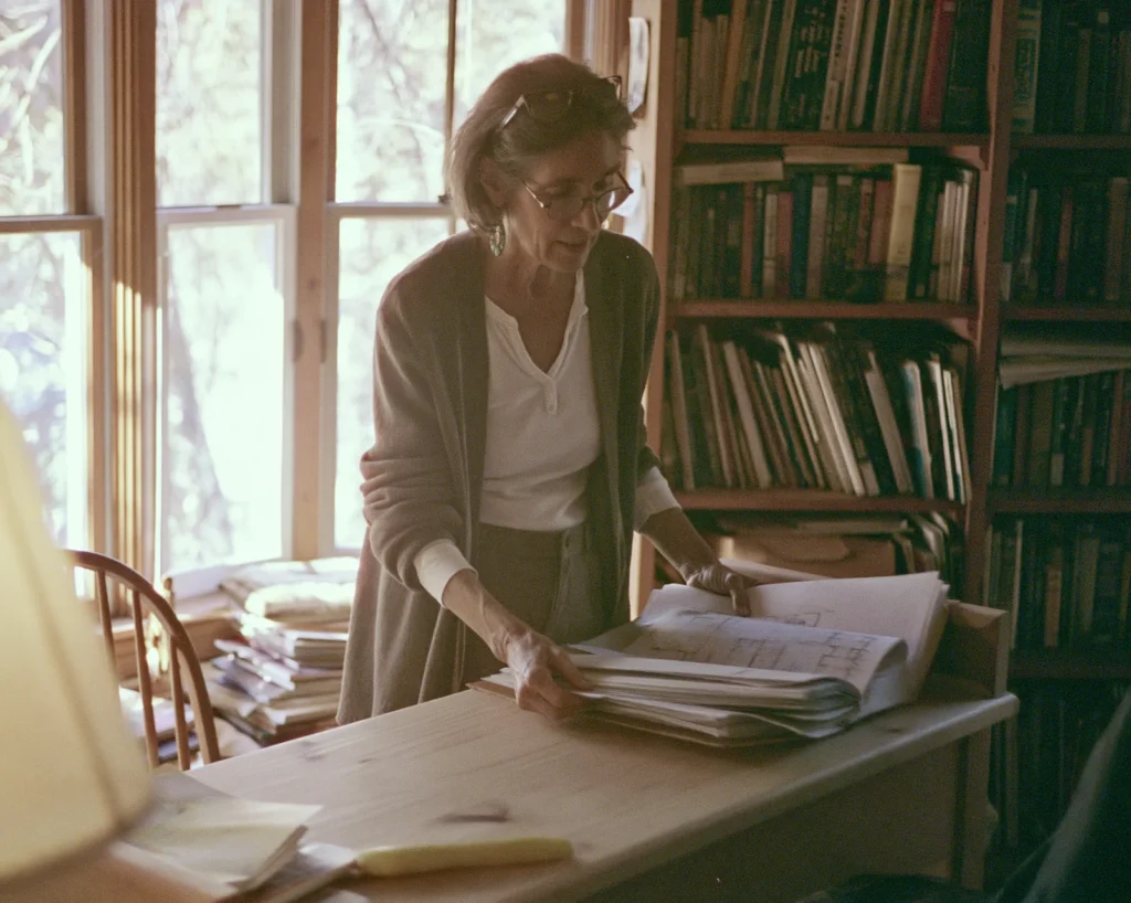 A business owner gathers printed growth plans into a folder at her desk