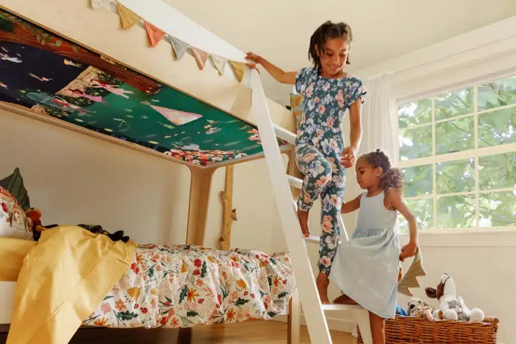 Underbunks client highlight: kids climbing a bunk bed ladder in floral pajamas